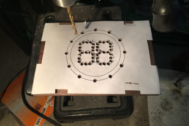 To start, he found a thin piece of wood and made a template for the clock face on some blank paper. After the template was lined up, he drilled small holes into the wood. These holes would later house the lights.