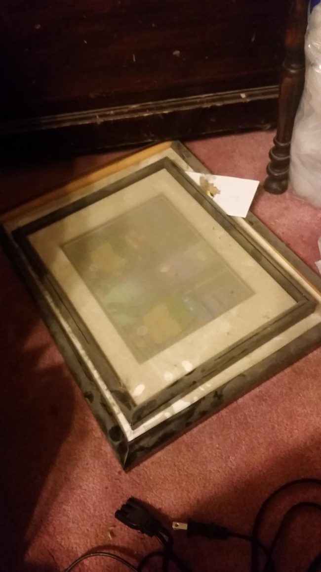 Under an armoire, he found a couple of framed pictures that were covered in dust.